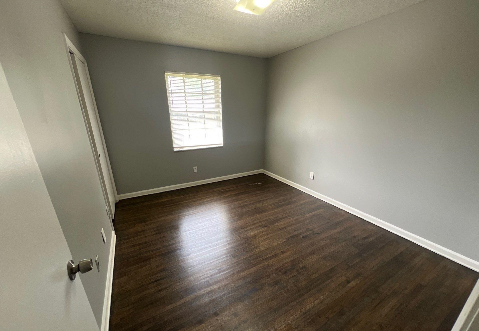 4936 Warrington Road Memphis, TN 38118 - Photo 11 of 13 an empty room with wooden floor and windows