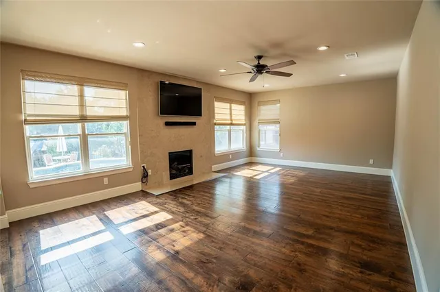 an empty room with windows fireplace and fans