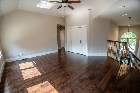 an empty room with wooden floor fan and windows