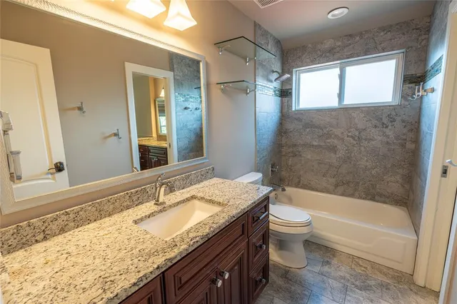 a bathroom with a granite countertop sink toilet and shower