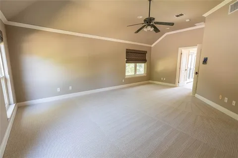 an empty room with a ceiling fan and windows