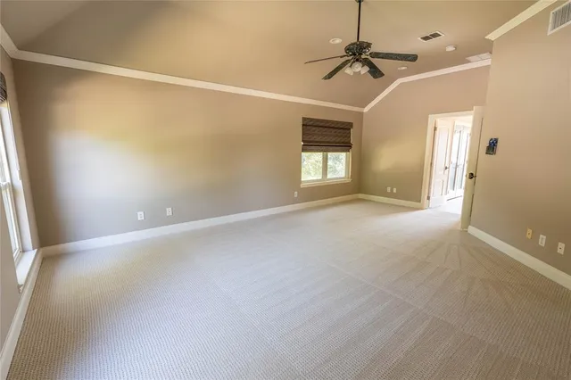 an empty room with a ceiling fan and windows