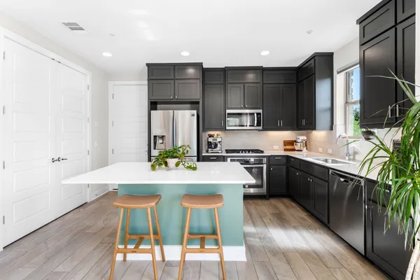 a kitchen with stainless steel appliances a dining table chairs stove refrigerator and cabinets