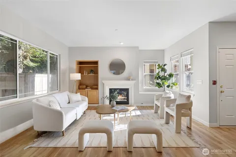 a living room with furniture a fireplace and potted plants with wooden floor
