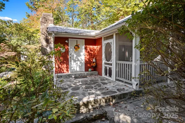 a view of a house with a small yard and floor to ceiling window and tree