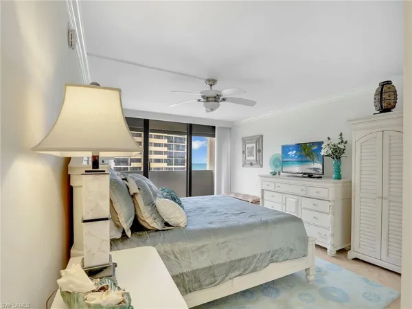 a bedroom with a large bed and a chandelier fan