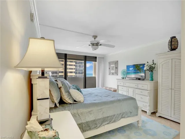 a bedroom with a large bed and a chandelier fan