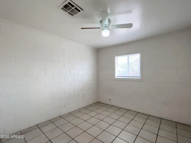 an empty room with windows and fan