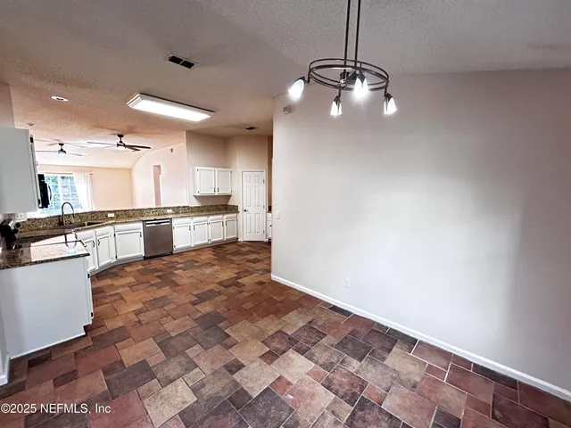 a large kitchen with granite countertop a stove a sink and a refrigerator