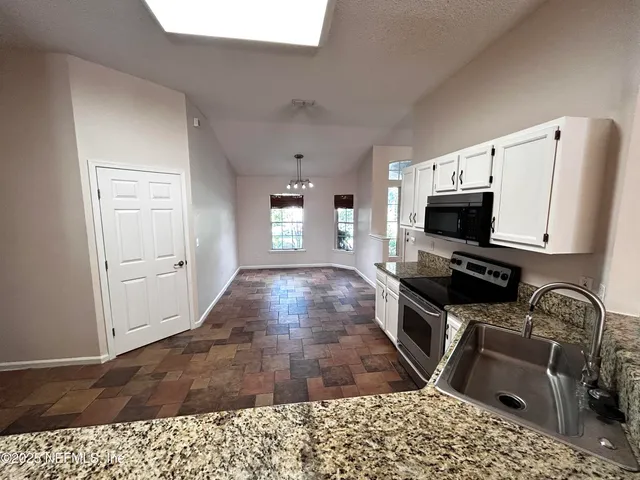 a kitchen with granite countertop a stove a sink and a microwave
