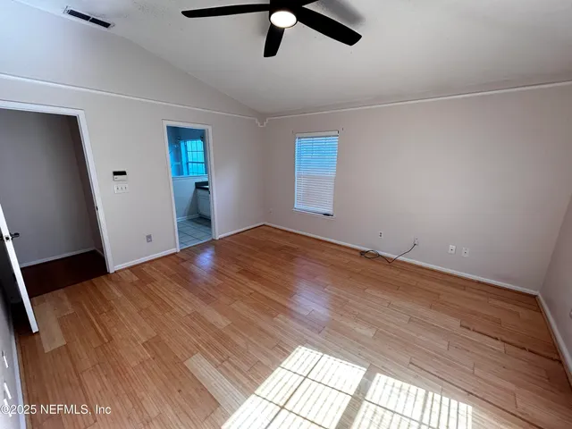 a view of empty room with wooden floor and window