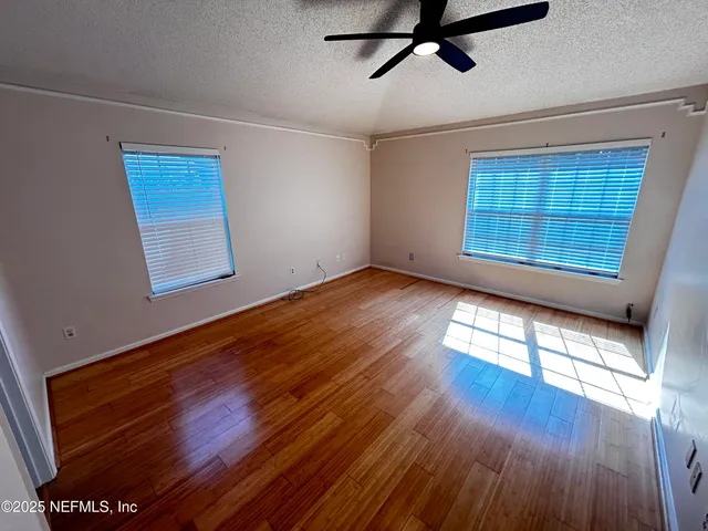 a view of empty room with wooden floor and fan