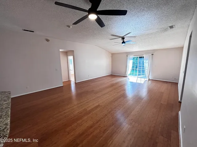 a view of an empty room with a window and wooden floor