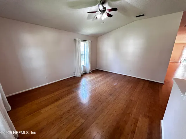 a view of an empty room with window and wooden floor