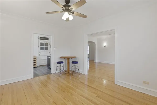 a view of empty room with wooden floor and fan