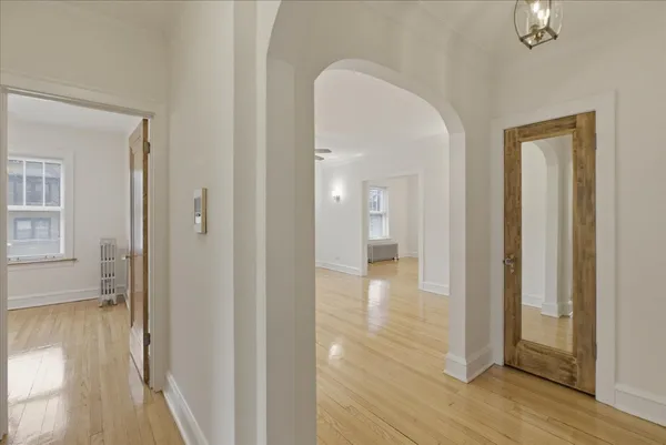 a view of a hallway with wooden floor and a bathroom