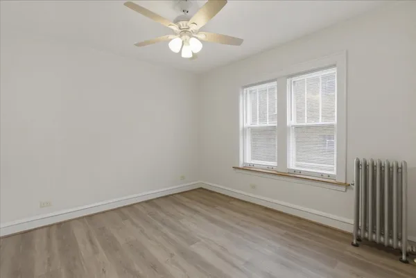 an empty room with wooden floor fan and windows