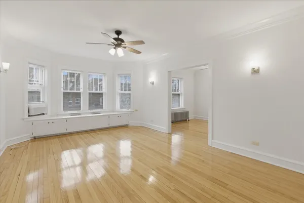 a view of empty room with wooden floor and fan