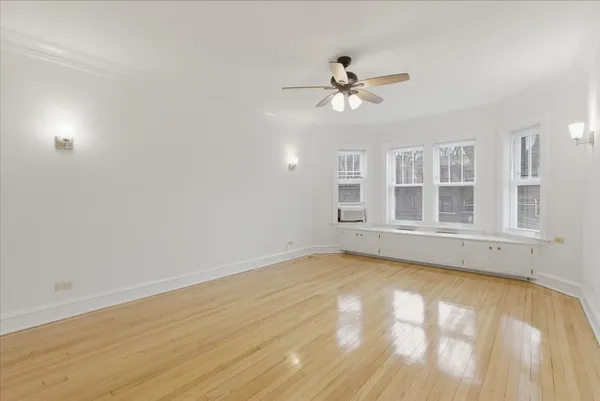 a view of an empty room with a window and wooden floor