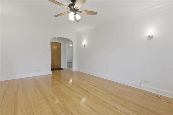 an empty room with wooden floor fan and windows