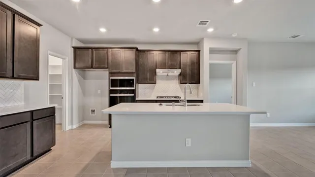 a kitchen with kitchen island granite countertop a sink stove and refrigerator