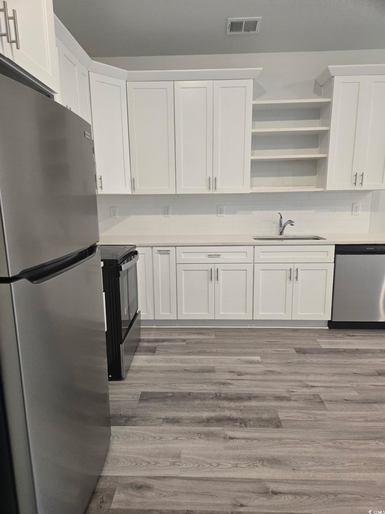 2027 6th Avenue Conway, SC 29526 - Photo 7 of 7 Kitchen with appliances with stainless steel finishes, white cabinetry, light wood-style floors, open shelves, and decorative backsplash