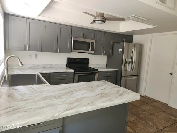 a kitchen with stainless steel appliances kitchen island a sink dishwasher a refrigerator and microwave