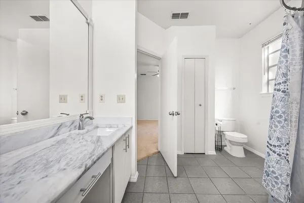 a bathroom with a granite countertop sink a toilet and bathtub