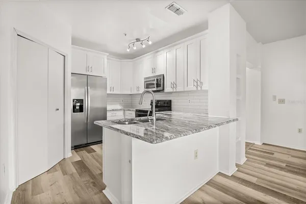 a kitchen with granite countertop stainless steel appliances a sink and cabinets