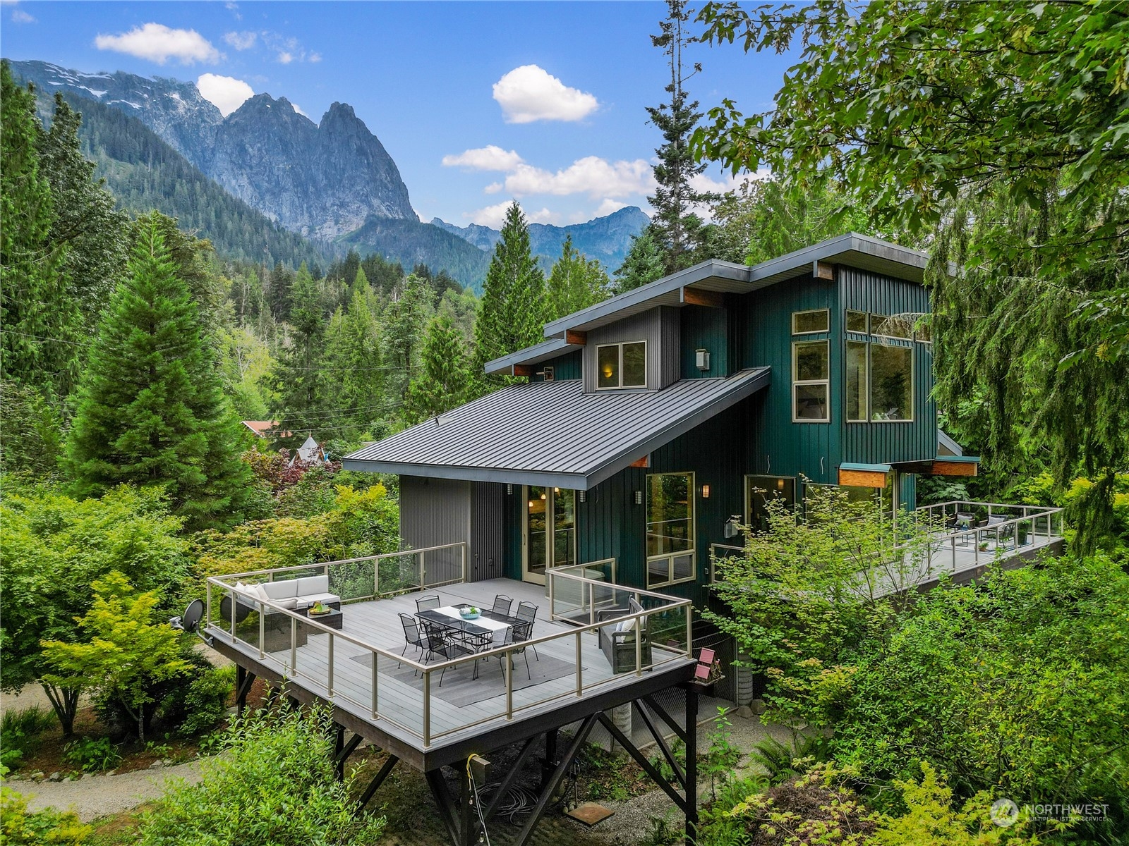 a backyard of a house with table and chairs potted plants and large tree