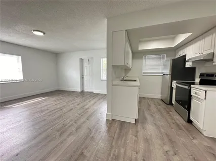 a view of a kitchen with wooden floor and electronic appliances