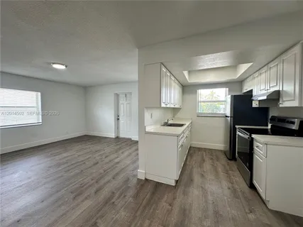 a kitchen with a refrigerator wooden floor and a sink