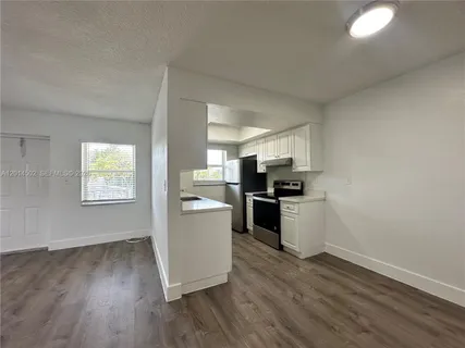 a kitchen with granite countertop a refrigerator and wooden floor