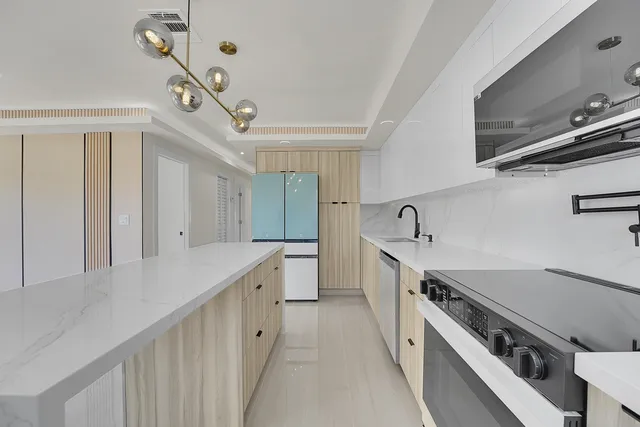 a kitchen with stainless steel appliances a stove a sink a microwave a refrigerator cabinets and living room view