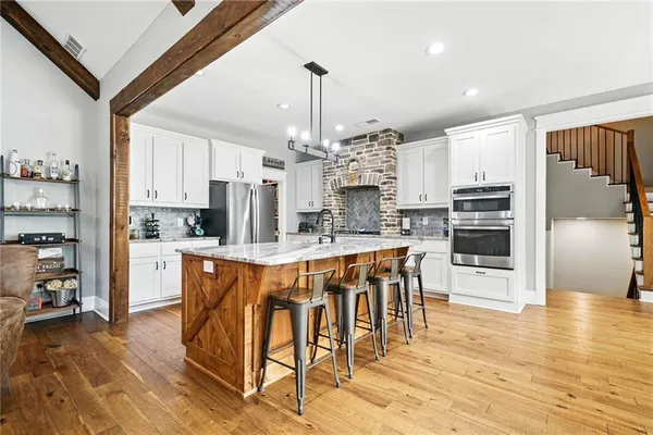 a kitchen with stainless steel appliances kitchen island granite countertop a sink stove and refrigerator