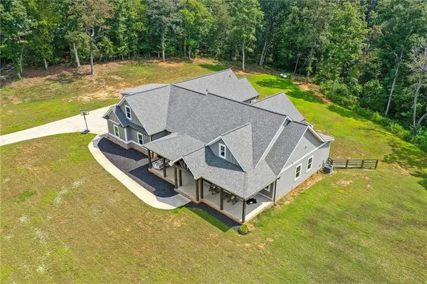 an aerial view of a house with swimming pool and large trees