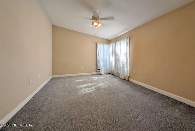 an empty room with windows and fan
