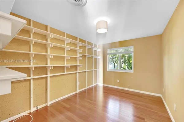 a view of an empty room with wooden floor and a window