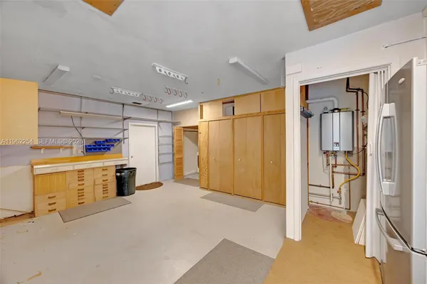 a view of a storage & utility room with closet fridge and a window