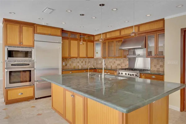 a kitchen with stainless steel appliances granite countertop a sink a stove and a refrigerator
