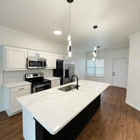 a kitchen with stainless steel appliances kitchen island a sink dishwasher a stove and a refrigerator with wooden floor