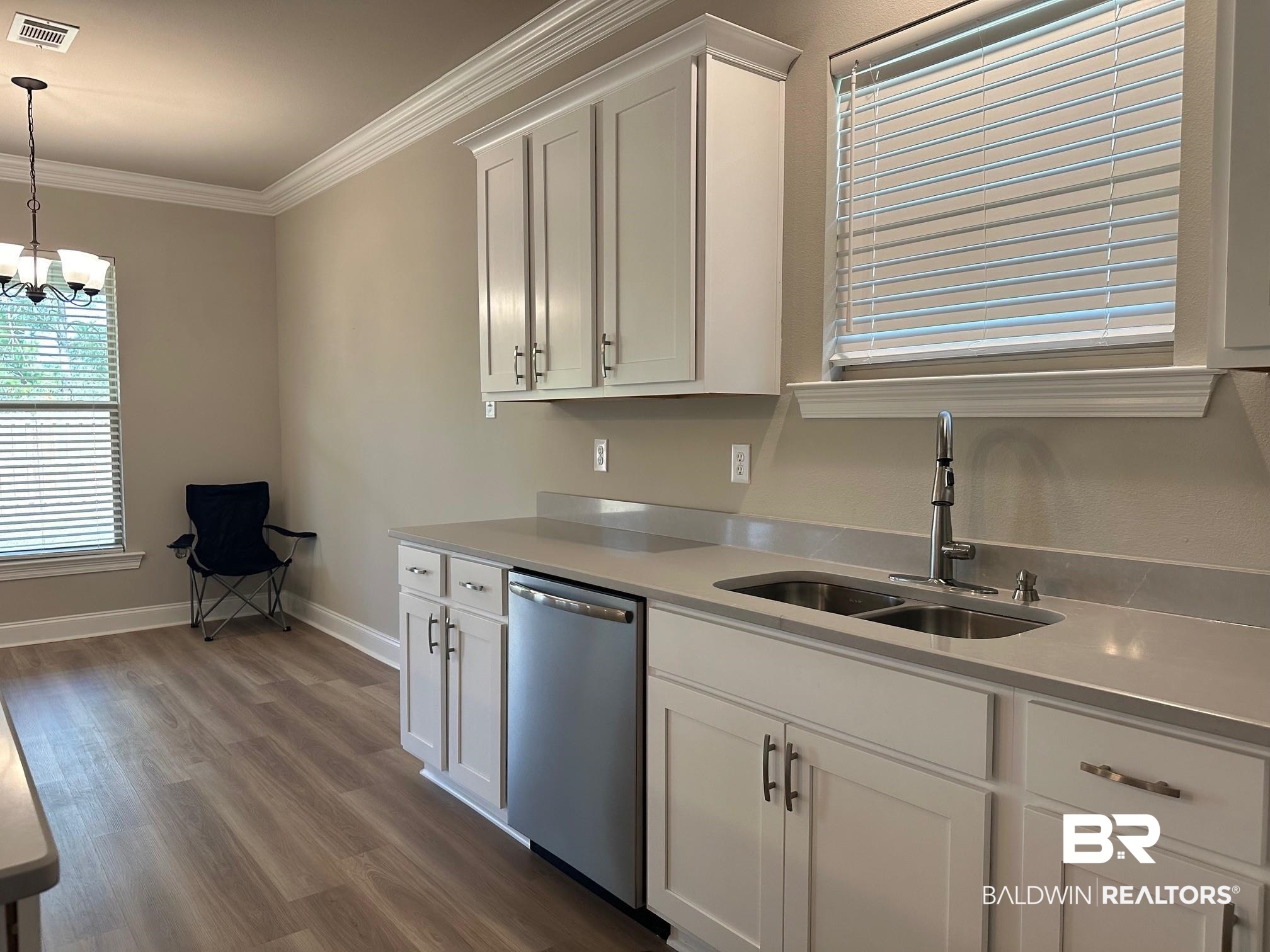 1009 Ruisseau Drive Foley, AL 36535 - Photo 28 of 55 Kitchen featuring dishwasher, hardwood / wood-style floors, sink, crown molding, and white cabinets