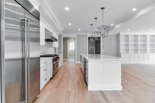 a large kitchen with granite countertop a large counter top a sink stainless steel appliances and cabinets