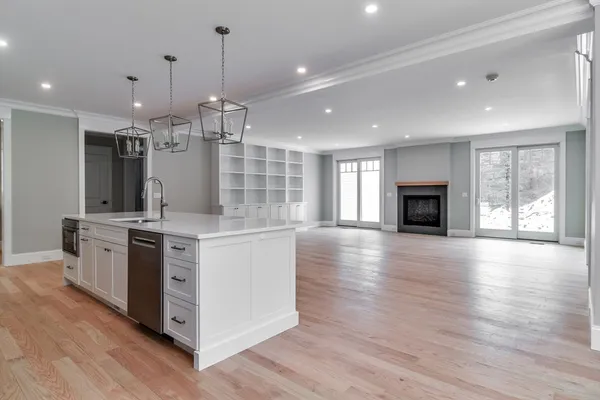 a kitchen with stainless steel appliances granite countertop a refrigerator a stove top oven a sink dishwasher and a fireplace with wooden floor