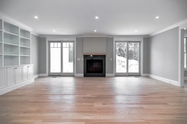 an empty room with wooden floor fireplace and windows