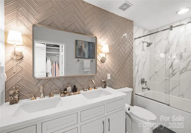 a bathroom with a sink toilet double vanity and shower