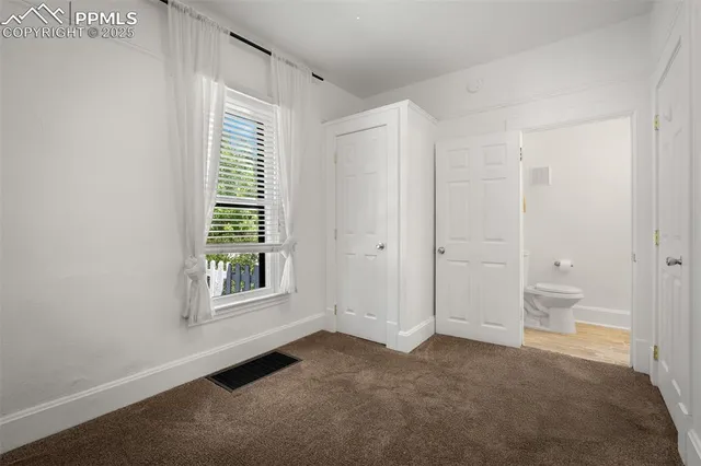 a view of an empty room with a bathroom and a window