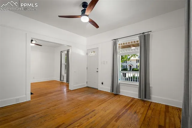 a view of an empty room with wooden floor and a window