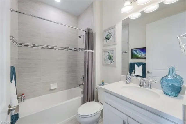 a bathroom with a granite countertop sink a toilet a mirror and shower