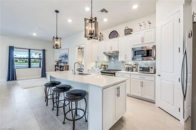 a kitchen with stainless steel appliances kitchen island a table chairs sink and cabinets